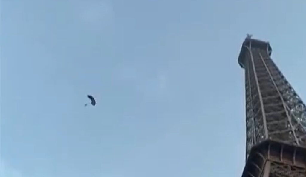 Man beklimt de Eiffeltoren en springt naar beneden, omstanders filmen het